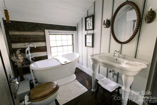 bathroom with hardwood / wood-style flooring, vaulted ceiling, toilet, and a bathing tub