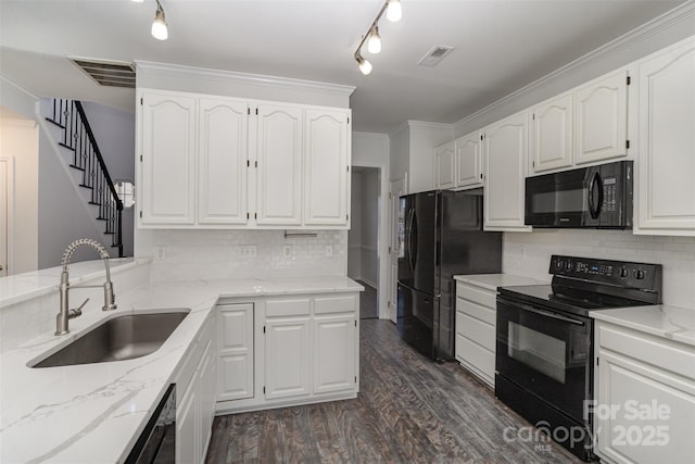 kitchen with light stone counters, white cabinets, sink, and black appliances