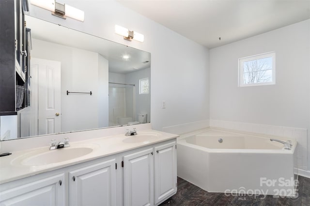 bathroom with a bathing tub, hardwood / wood-style floors, vanity, and toilet