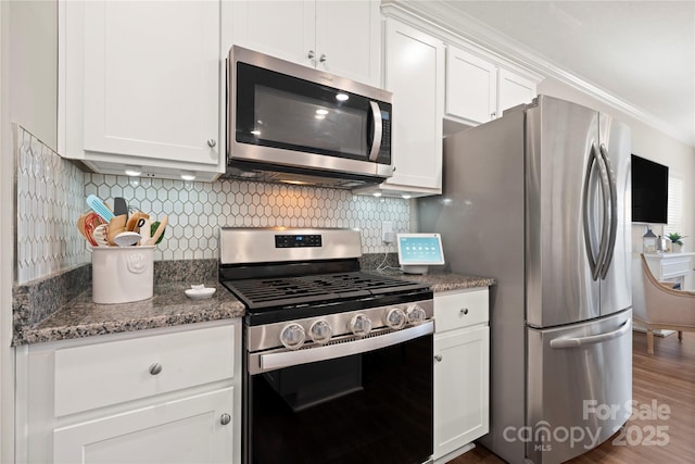 kitchen featuring backsplash, stainless steel appliances, white cabinets, dark hardwood / wood-style flooring, and dark stone counters