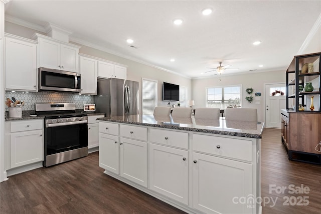 kitchen featuring stainless steel appliances, a center island, white cabinets, and dark stone counters