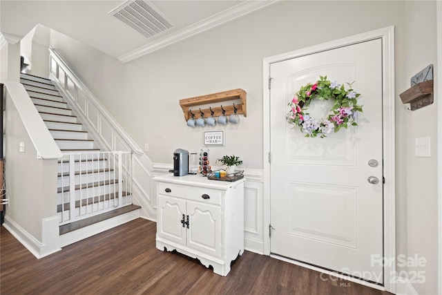 foyer with ornamental molding and dark hardwood / wood-style floors