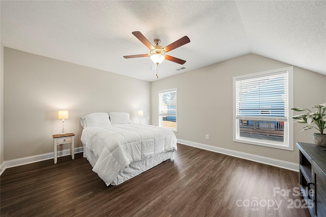 bedroom with lofted ceiling, ceiling fan, dark hardwood / wood-style floors, and a textured ceiling