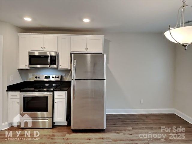 kitchen with wood-type flooring, white cabinets, and appliances with stainless steel finishes