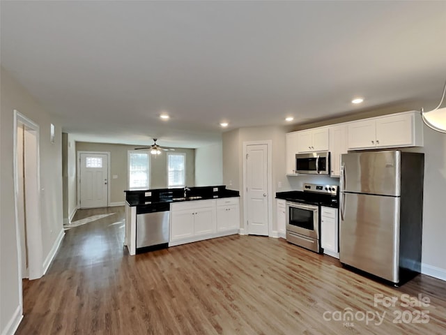 kitchen with stainless steel appliances, white cabinets, and light hardwood / wood-style flooring