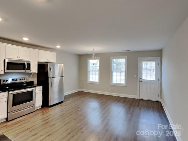 kitchen featuring white cabinetry, stainless steel appliances, light hardwood / wood-style floors, and pendant lighting