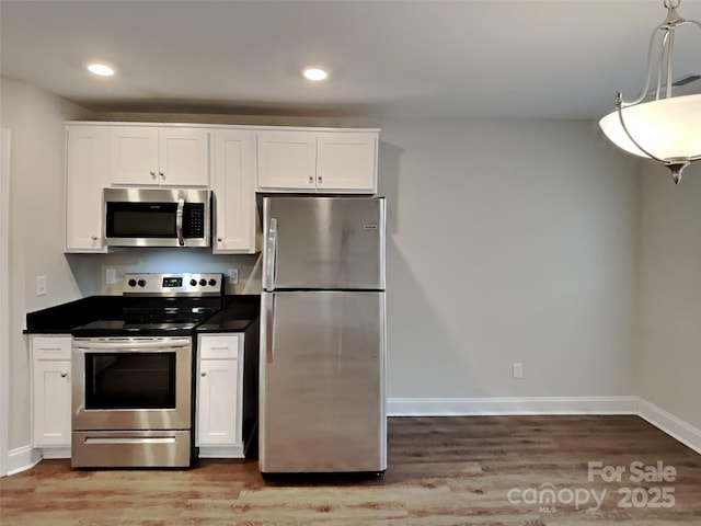 kitchen with white cabinetry, stainless steel appliances, hardwood / wood-style floors, and hanging light fixtures