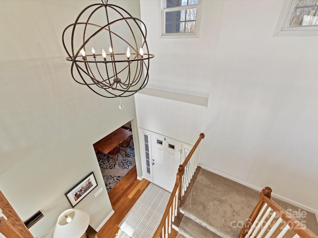 staircase with plenty of natural light, hardwood / wood-style floors, and a notable chandelier