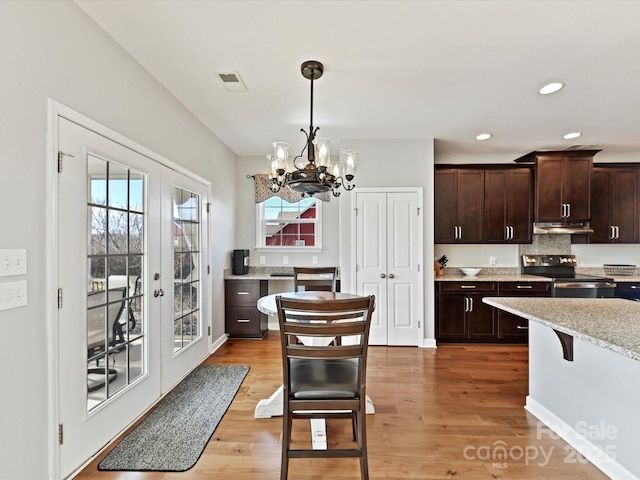 kitchen with french doors, light stone counters, dark brown cabinets, stainless steel electric stove, and hardwood / wood-style floors