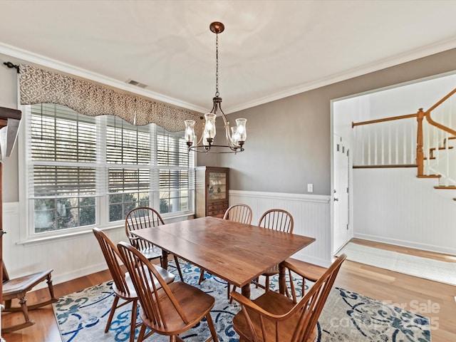 dining space featuring crown molding, wood-type flooring, and a notable chandelier