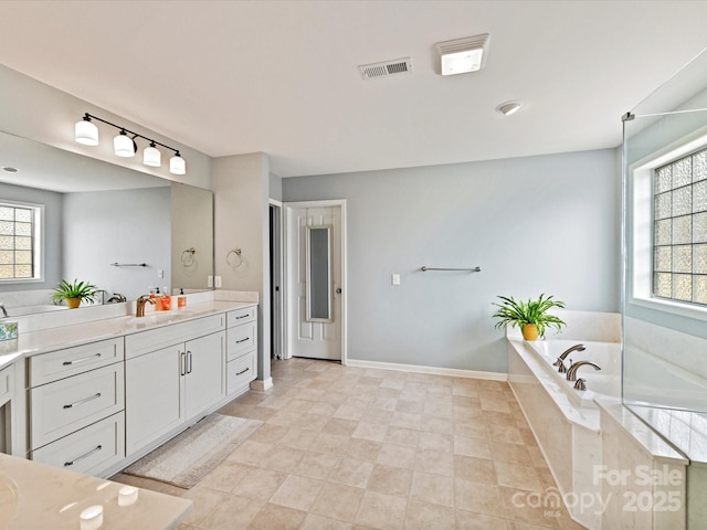 bathroom featuring vanity, a wealth of natural light, and tiled bath