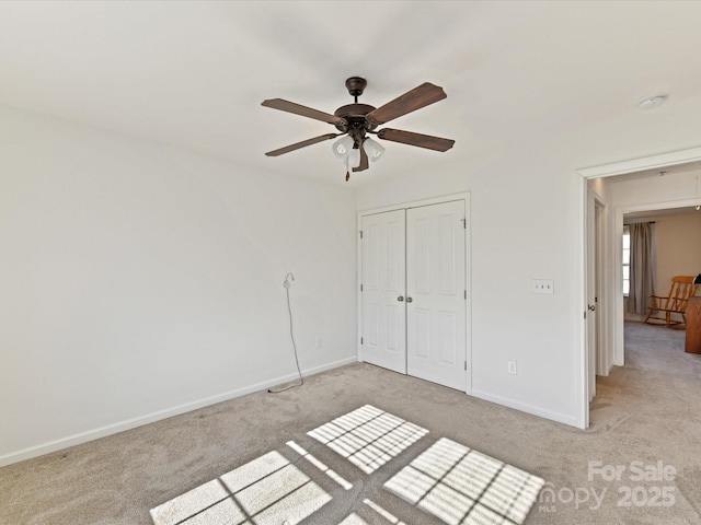 unfurnished bedroom featuring light carpet, a closet, and ceiling fan