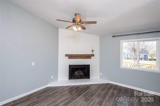 unfurnished living room featuring ceiling fan, a large fireplace, and dark hardwood / wood-style flooring