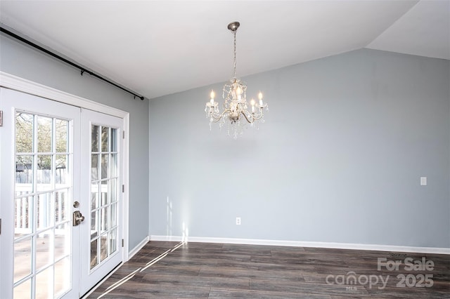 unfurnished dining area featuring lofted ceiling, a notable chandelier, dark hardwood / wood-style flooring, and french doors