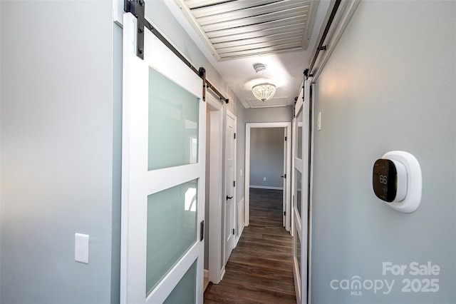 hallway with dark wood-type flooring and a barn door