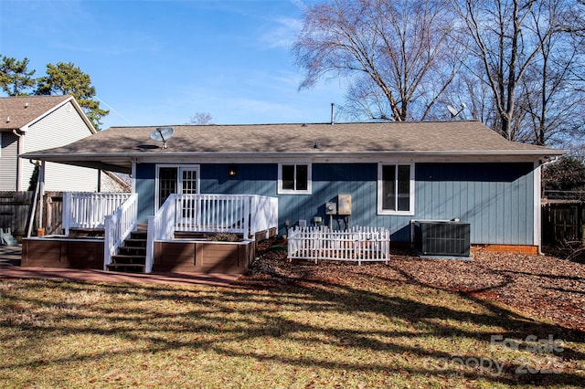 rear view of house with cooling unit, a wooden deck, and a yard