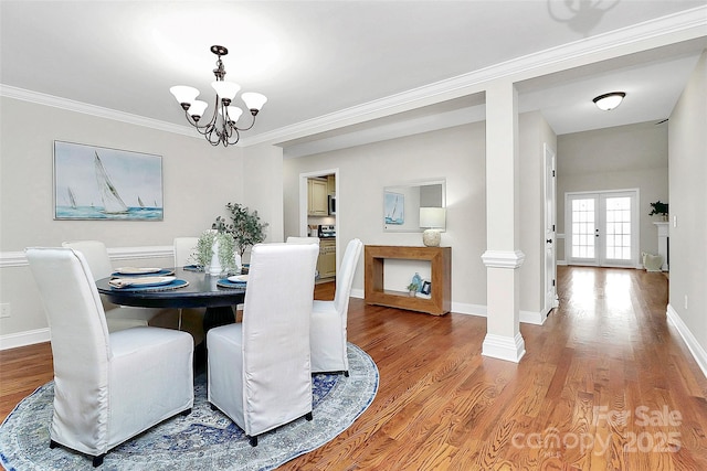 dining space with a notable chandelier, wood finished floors, french doors, decorative columns, and crown molding