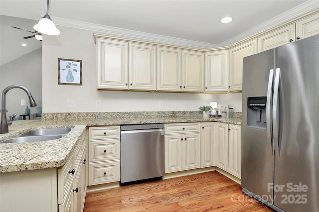 kitchen featuring cream cabinetry, stainless steel appliances, light wood-style floors, a sink, and light stone countertops