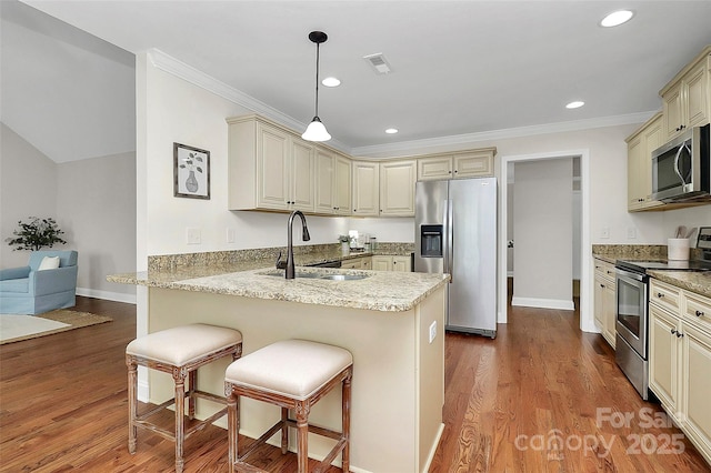 kitchen featuring appliances with stainless steel finishes, pendant lighting, a sink, and cream cabinetry