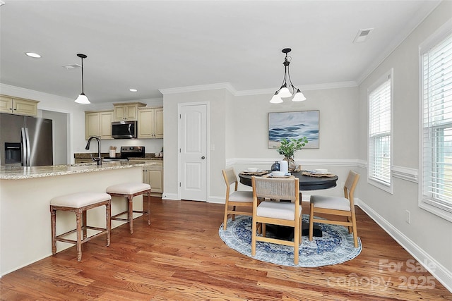 dining area featuring crown molding, baseboards, visible vents, and light wood-style floors