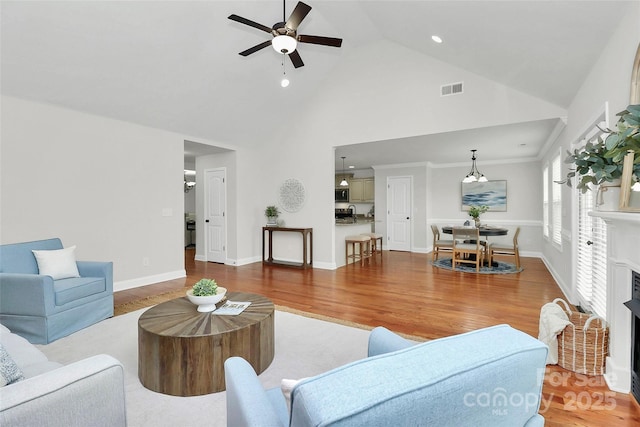 living area with a fireplace, visible vents, and wood finished floors