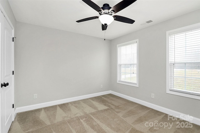 carpeted spare room featuring ceiling fan, visible vents, and baseboards