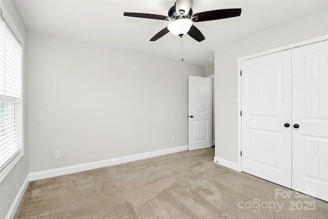 unfurnished bedroom with light carpet, multiple windows, baseboards, and a closet