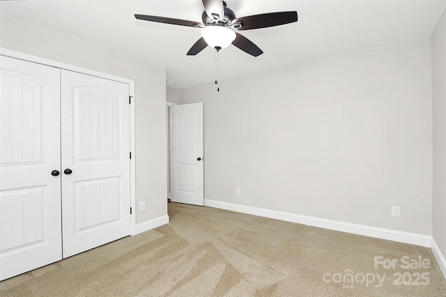 unfurnished bedroom featuring baseboards, a closet, a ceiling fan, and light colored carpet