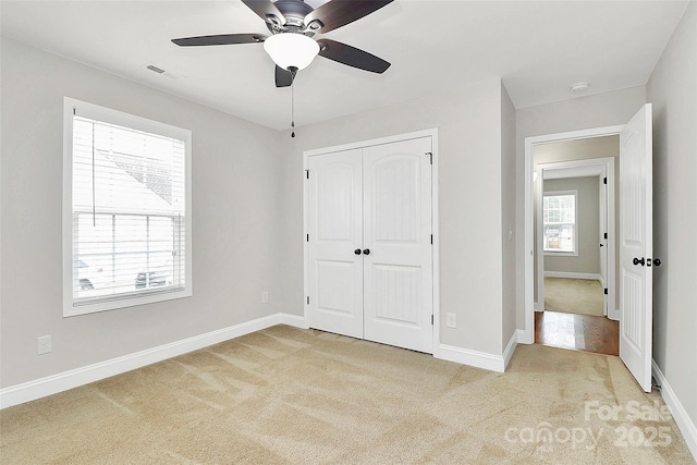 unfurnished bedroom featuring a closet, light carpet, and baseboards