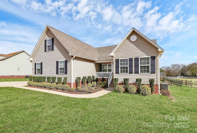 view of front of property with a front lawn, roof with shingles, central AC unit, and fence