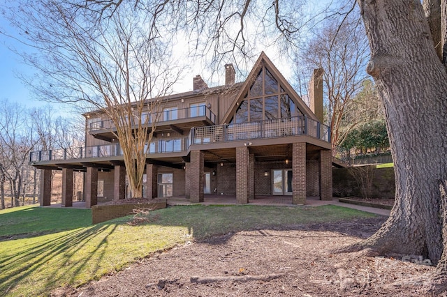 view of front of property with a patio, a chimney, a deck, a front yard, and brick siding