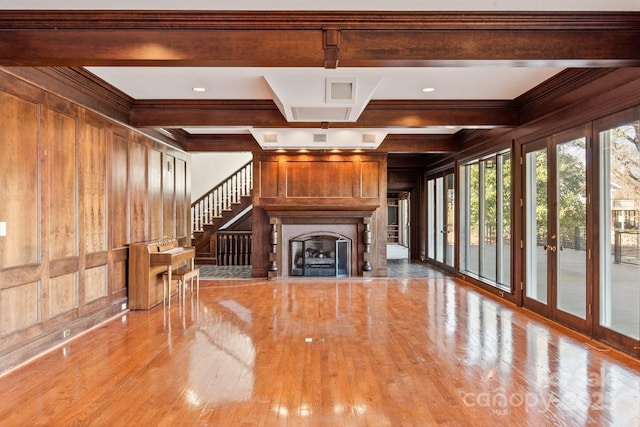 unfurnished living room featuring coffered ceiling, a fireplace with flush hearth, light wood-type flooring, wood walls, and beam ceiling