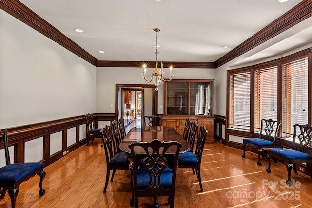 dining space with crown molding, recessed lighting, wainscoting, wood finished floors, and a chandelier