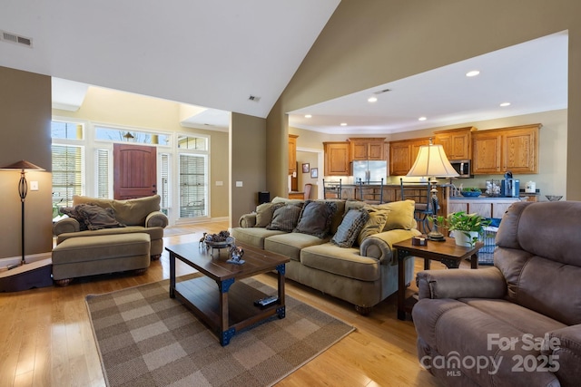 living room with high vaulted ceiling and light wood-type flooring