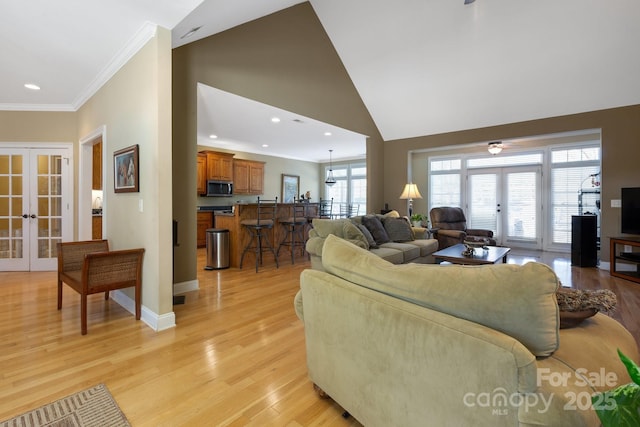 living room with crown molding, light hardwood / wood-style flooring, high vaulted ceiling, and french doors