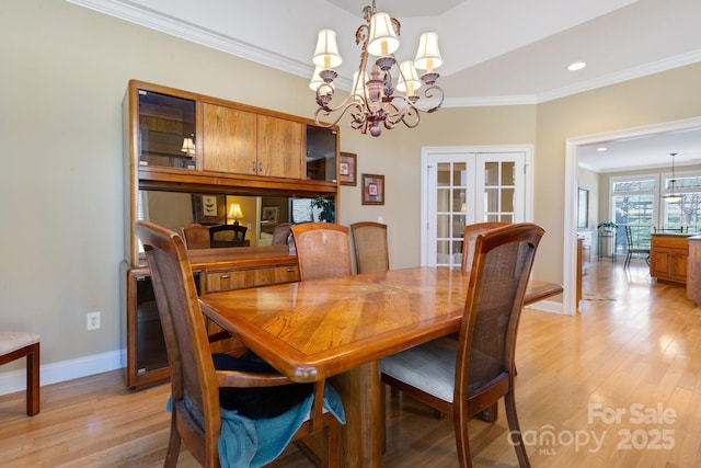 dining room with crown molding, light wood-type flooring, a chandelier, and french doors