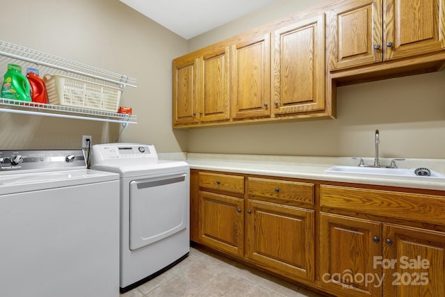 clothes washing area with cabinets, sink, light tile patterned floors, and independent washer and dryer