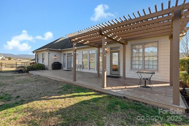 back of house with a pergola, a deck, and a lawn