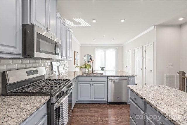 kitchen with gray cabinets, sink, light stone counters, stainless steel appliances, and crown molding