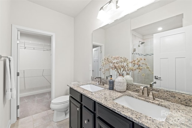 bathroom featuring vanity, tile patterned floors, toilet, and a tile shower