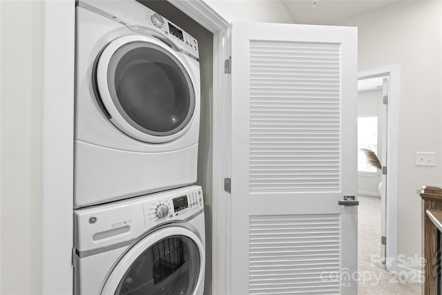 laundry room featuring stacked washer and clothes dryer and carpet