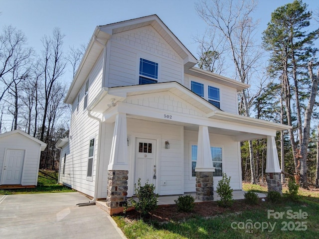 craftsman house featuring covered porch and a shed