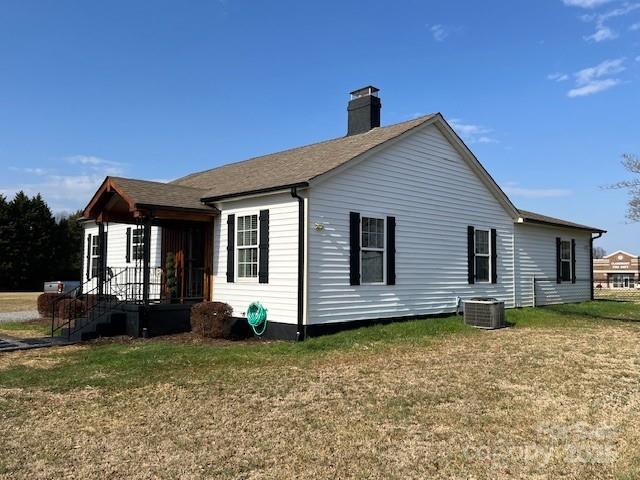 back of house with central AC unit and a lawn