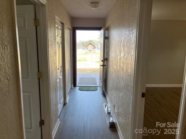 corridor with wood-type flooring and a textured ceiling