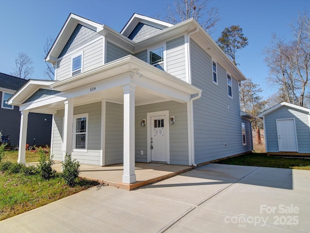 view of front of house with covered porch and a storage shed