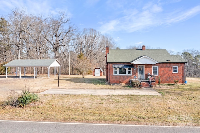 view of front of property featuring a carport, a front yard, and a storage shed