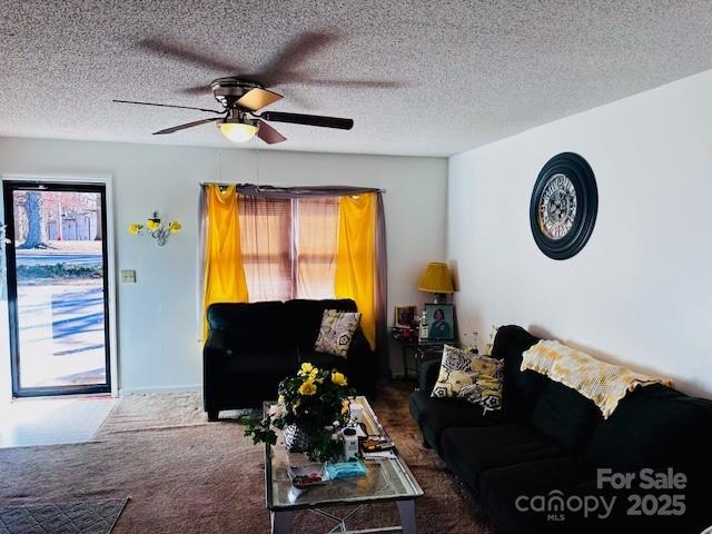 living area featuring a wealth of natural light, dark carpet, a textured ceiling, and ceiling fan