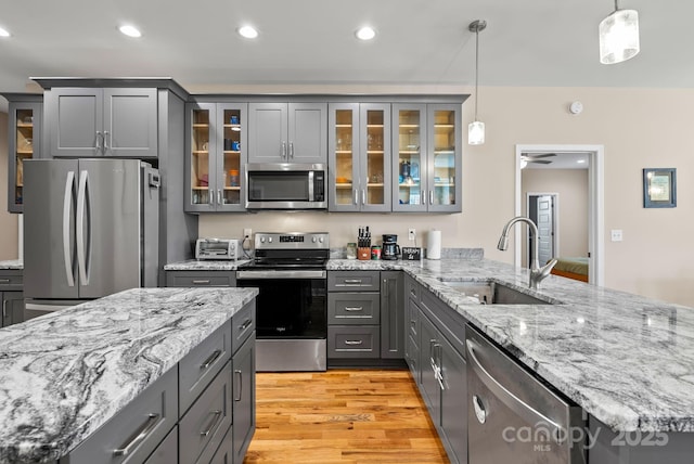 kitchen with pendant lighting, appliances with stainless steel finishes, gray cabinets, and sink