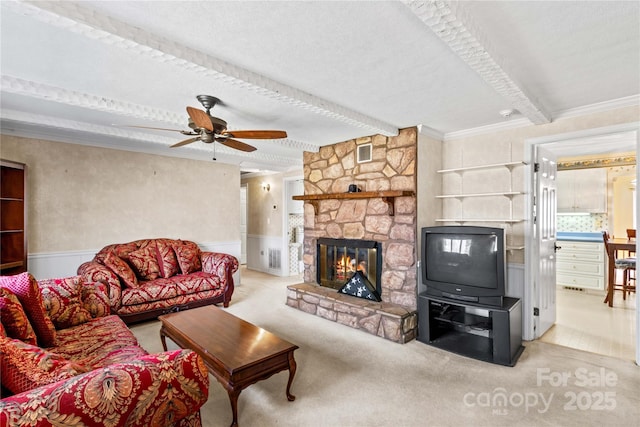 living room featuring a stone fireplace, beamed ceiling, ornamental molding, ceiling fan, and light carpet