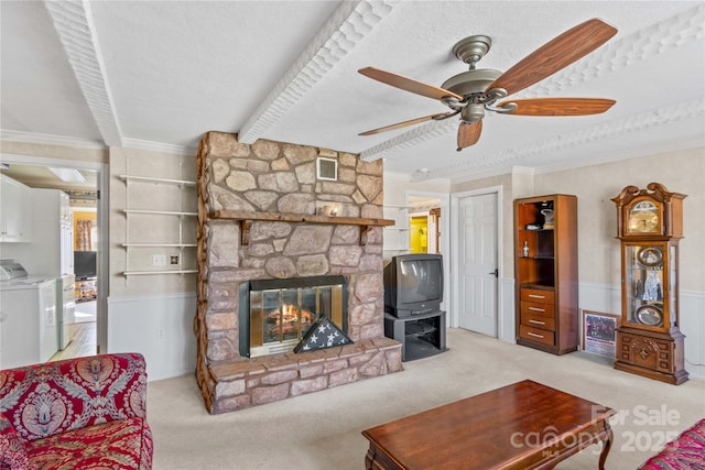 carpeted living room with separate washer and dryer, a stone fireplace, crown molding, and a textured ceiling